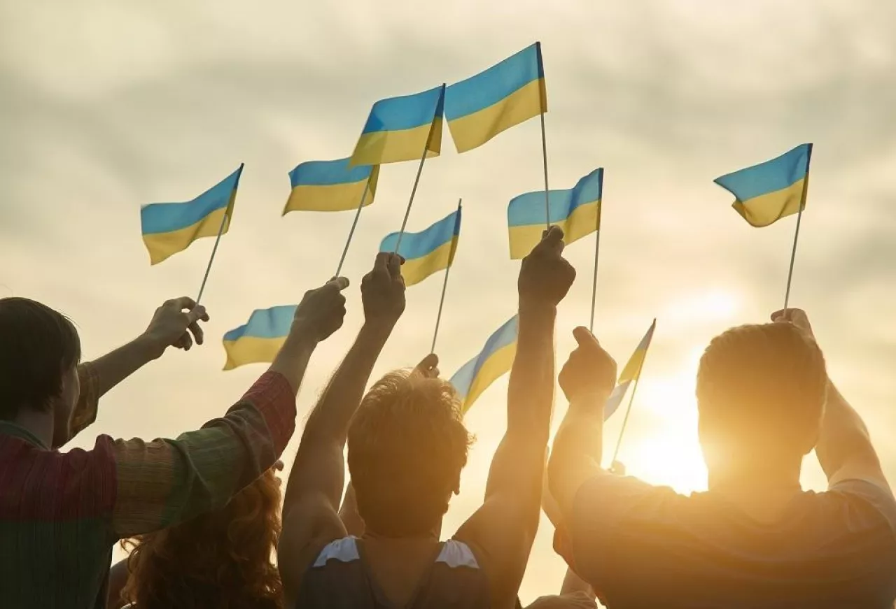 Crowd with ukrainian flags in the evening. Ukrainian revolution. Evening sunny sky background.