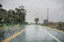 Raindrops on the windshield on a rainy day; empty street in the background; California