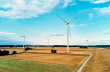 Windmill among agricultural fields. Wind turbine generator at summer day. Wind energy concept, Suistanable and renewable energy for climate protection
