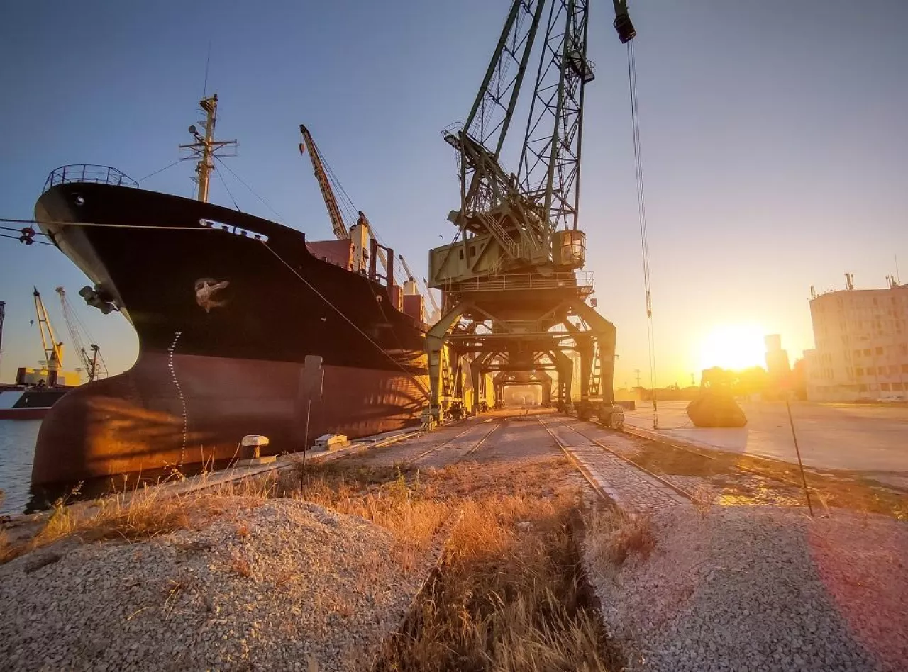 big cargo ship bulk carrier is loaded with grain of wheat in port at sunset