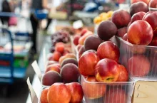 Picture of sweet, tasty and fresh peaches lying in small plastic boxes in the store.