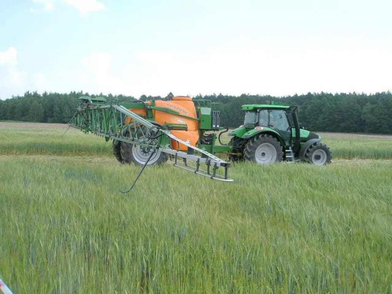 Ciągnik z opryskiwaczem na polu